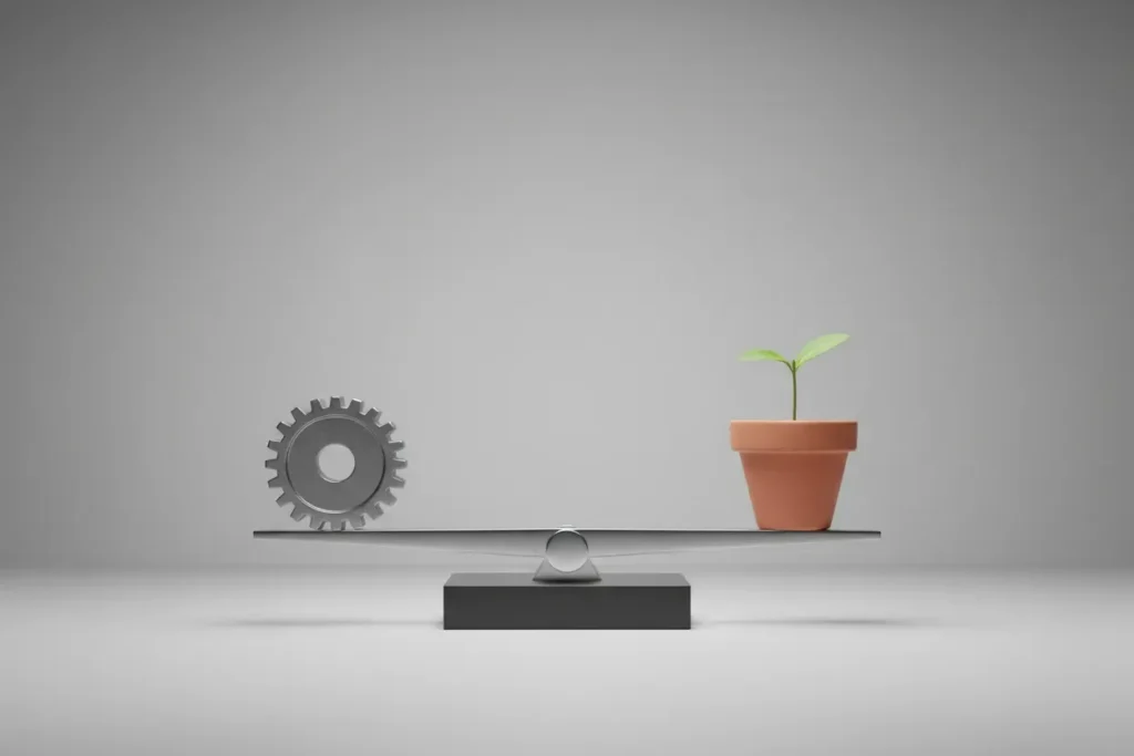 Modern balance scale with a metal gear and a potted green sprout, nearly level on a soft gray background.